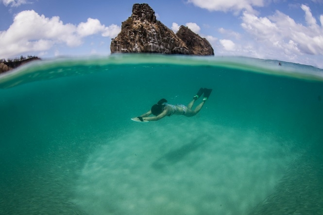 mulher de biquini mergulhando em um mar de água azul bem transparente